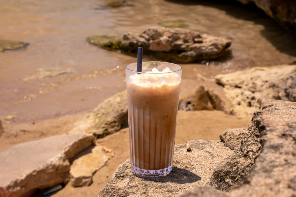 Iced coffee on the rocks beside the water