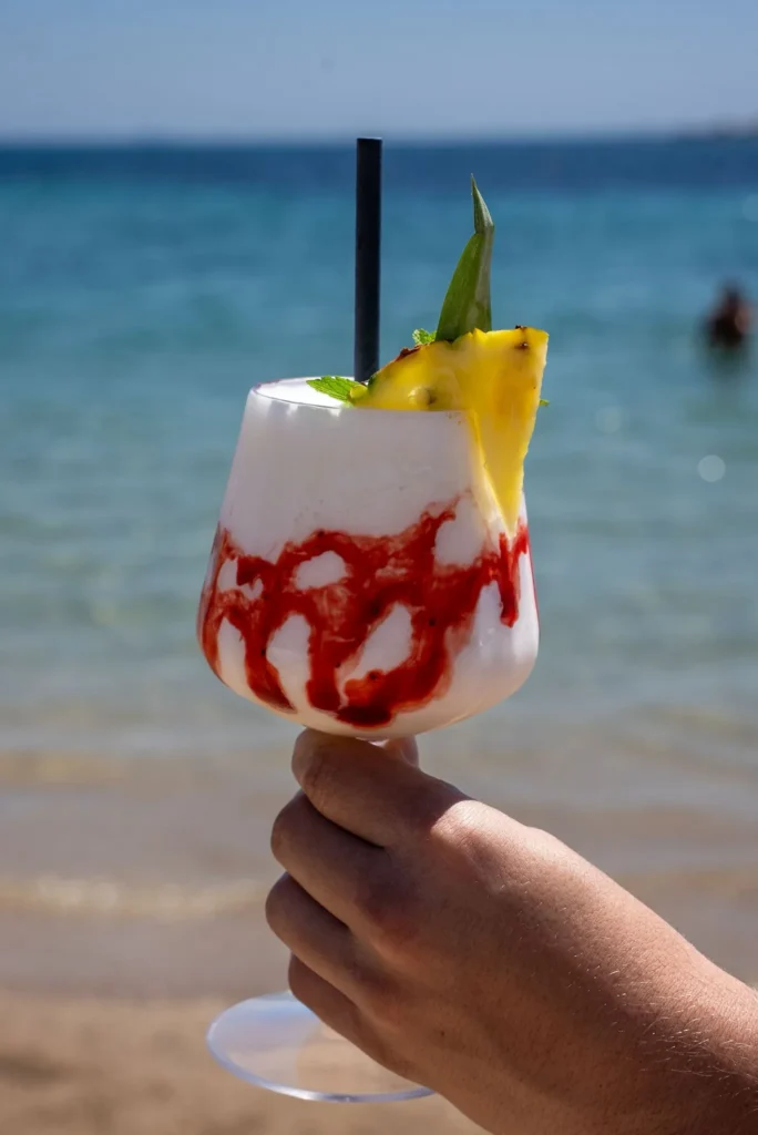 Frozen cocktail held up in front of the sea